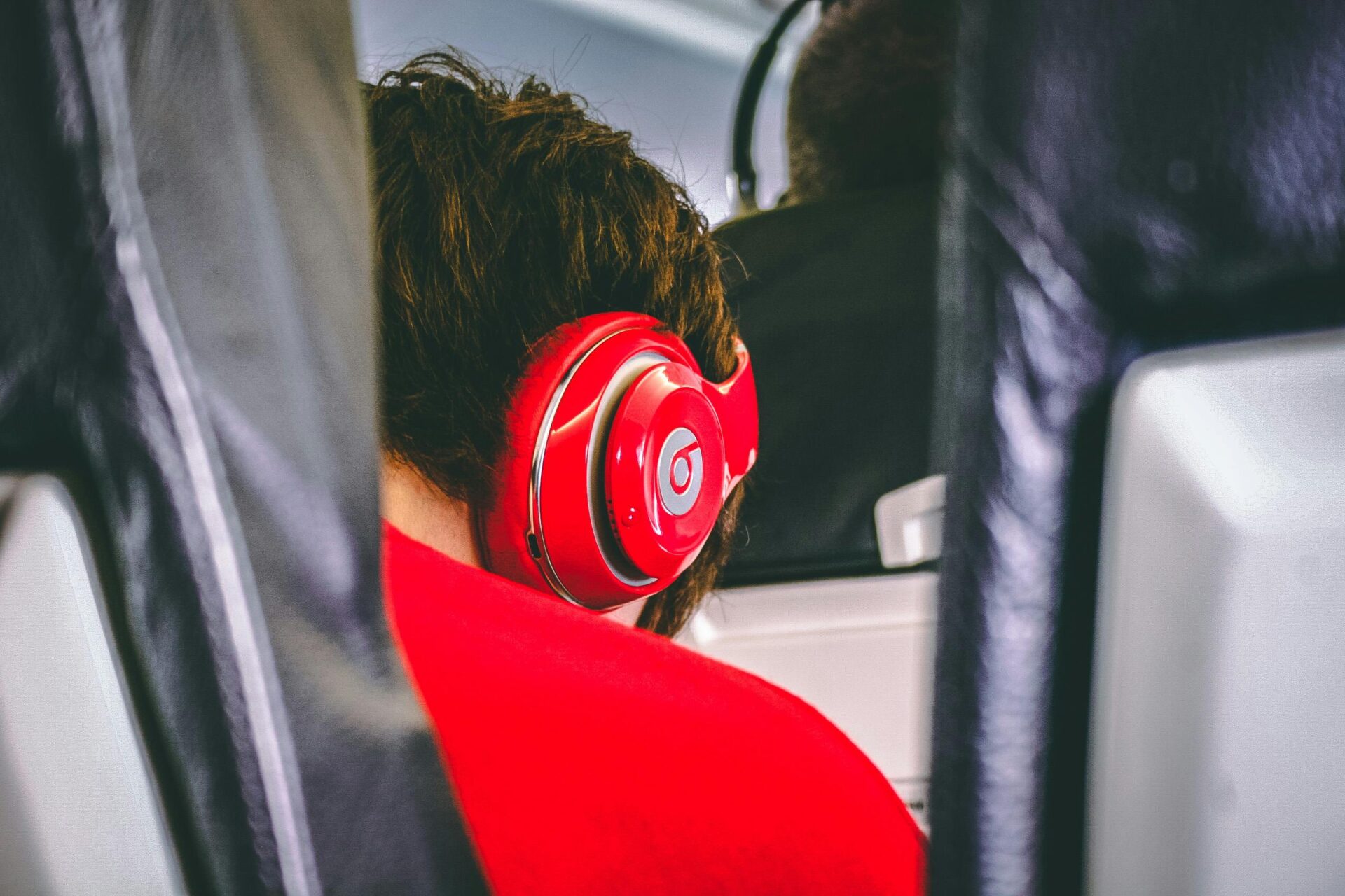 Boy with all red beats headphones while Traveling on a flight